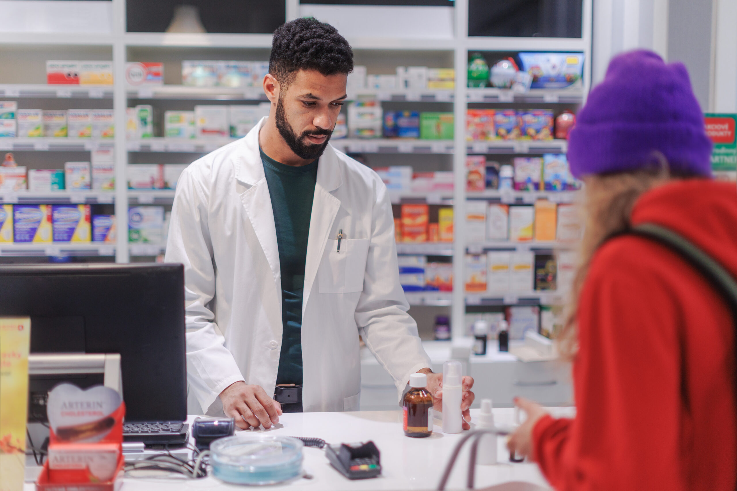 Multiracial pharmacist selling medications to young woman.